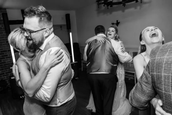 Wedding guests laughing and dancing together during an evening reception