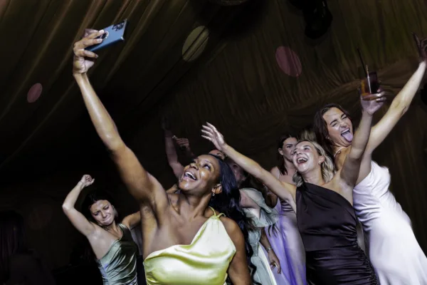 Wedding guests laughing, dancing and taking a selfie together during the evening reception.