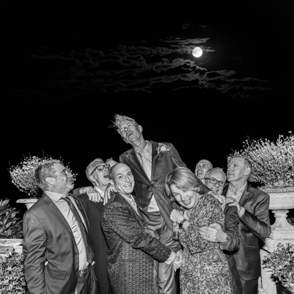 Wedding guests celebrating outdoors beneath a full moon at night.