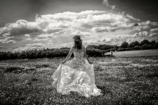 Bride walking through a wildflower meadow in a flowing floral wedding dress.