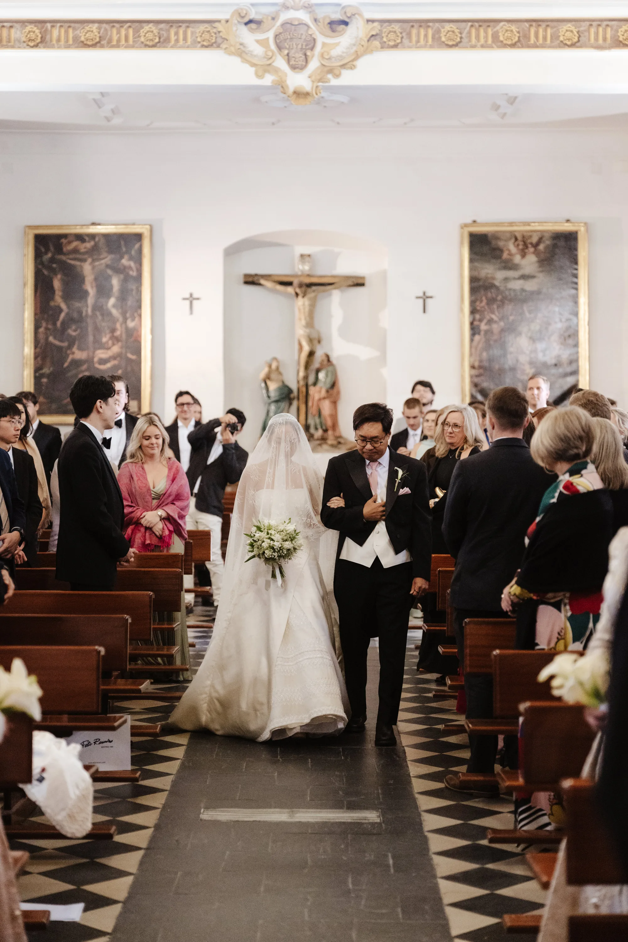 Wedding Toledo Spain Sam Sparks Photography 55 - A Multicultural Wedding in Toledo, Spain, with Korean Heritage and Deep Southern Roots Korean bride being assisted down the aisle by her father at the Santos Justo y Pastor church in Toledo, Spain.