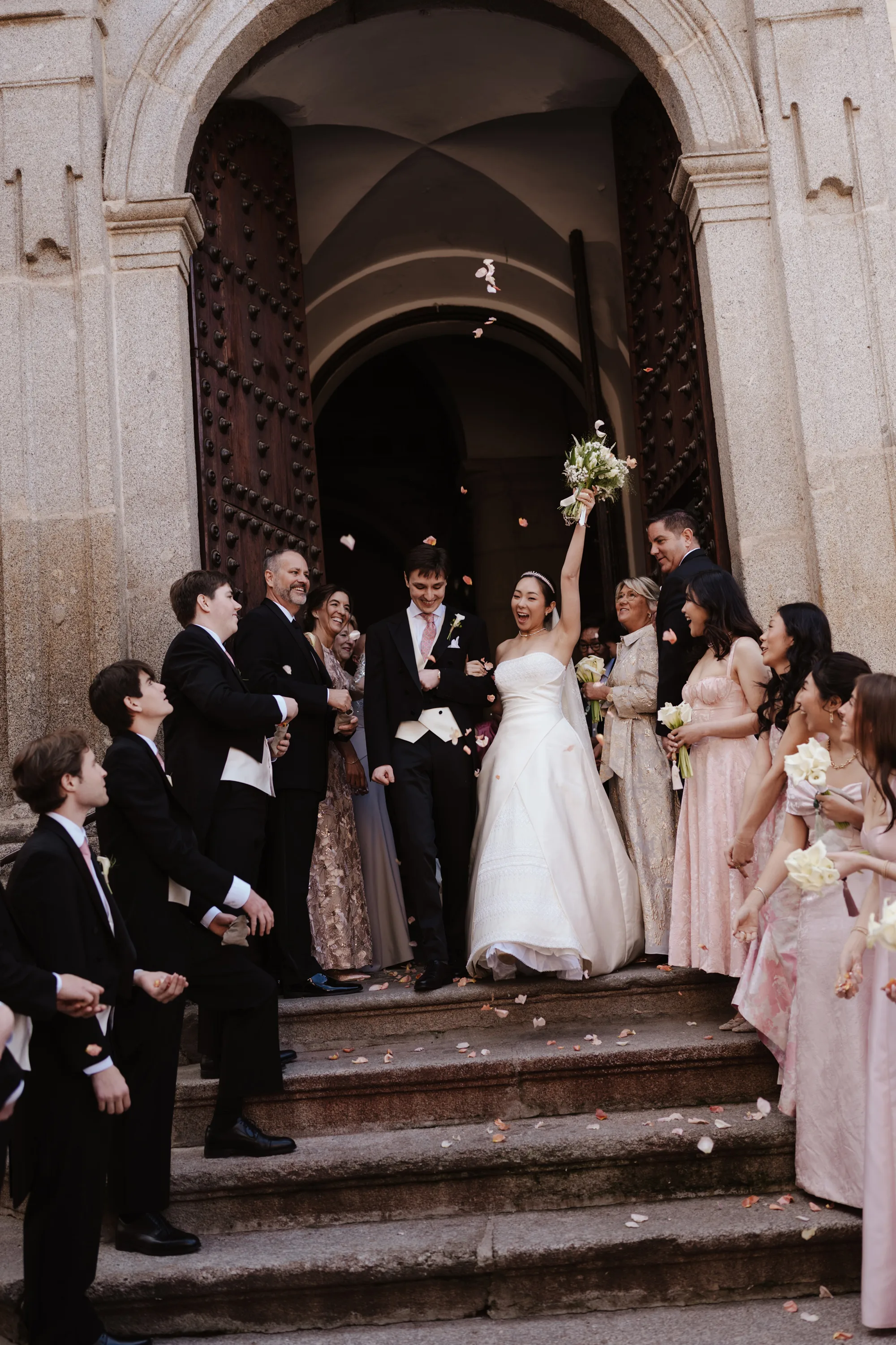 Wedding Toledo Spain Sam Sparks Photography 73 - A Multicultural Wedding in Toledo, Spain, with Korean Heritage and Deep Southern Roots Bride and groom exiting their Catholic wedding ceremony at the Santos Justo y Pastor church in Toledo, Spain to be greeted by their bridal party and showered in confetti.