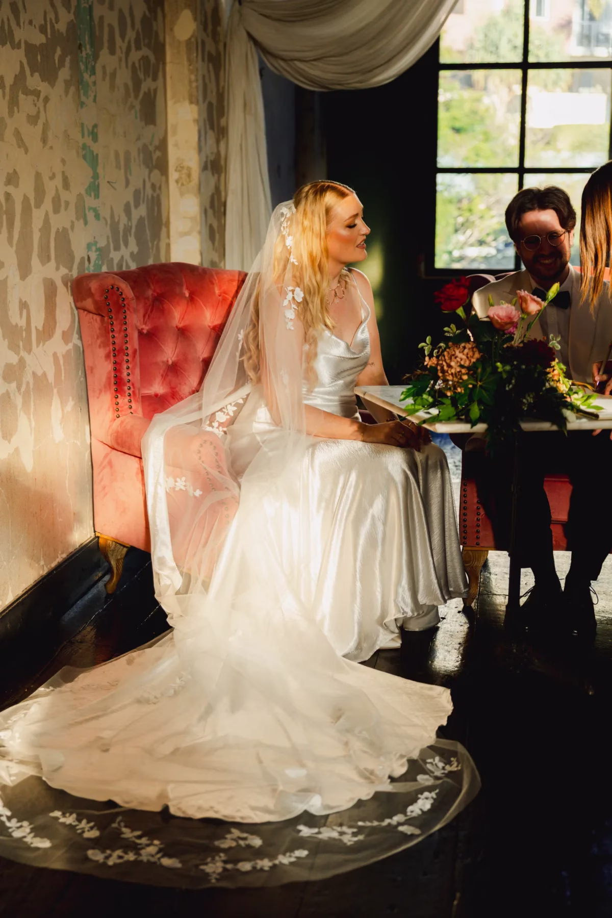 bride seated red armchair the light photo and film - The Light Photo & Film: 35mm Wedding Photography and Super 8 for Creative Couples Bride seated in a red upholstered armchair beside a window, with her wedding dress spread across the floor.