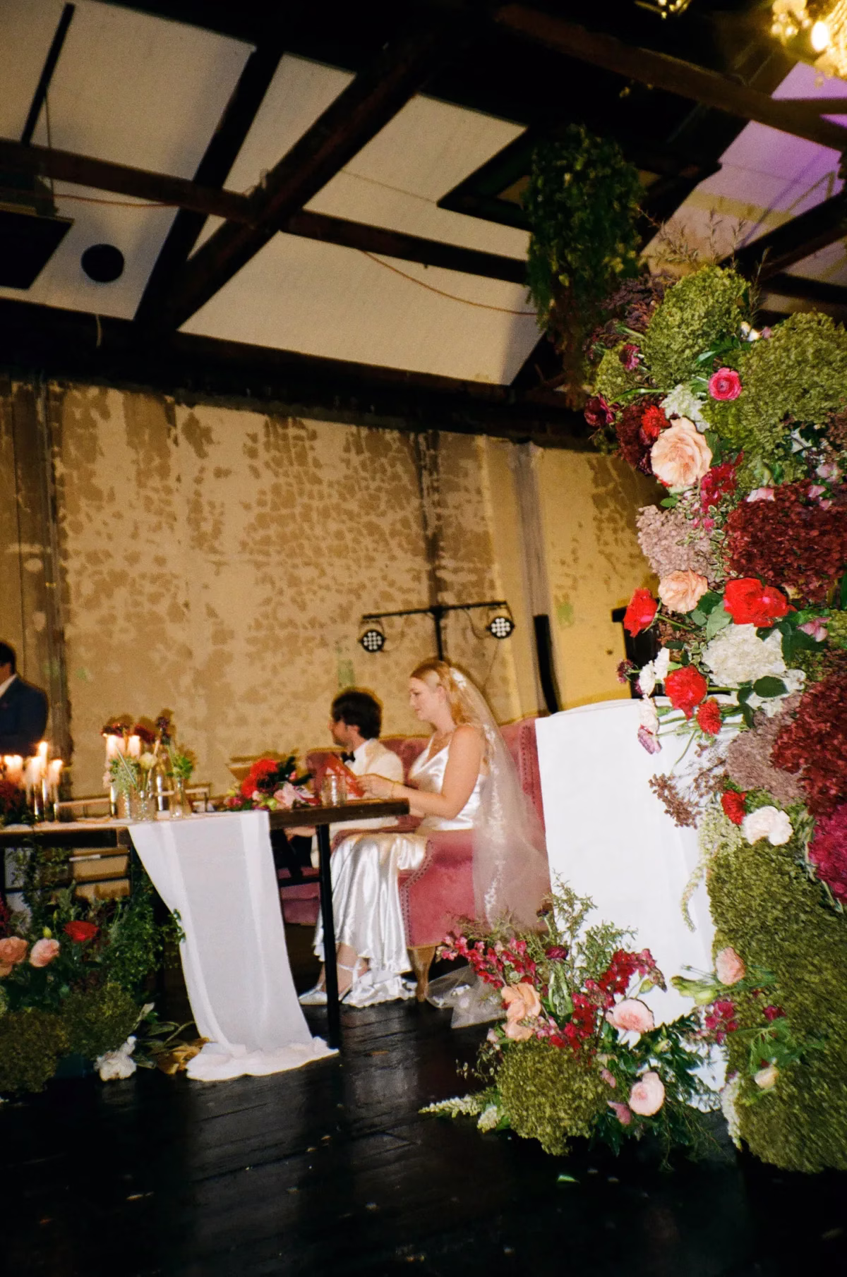 wedding reception colourful floral arrangements the light photo and film - The Light Photo & Film: 35mm Wedding Photography and Super 8 for Creative Couples Wedding reception tables surrounded by colourful floral arrangements beneath exposed ceiling beams.