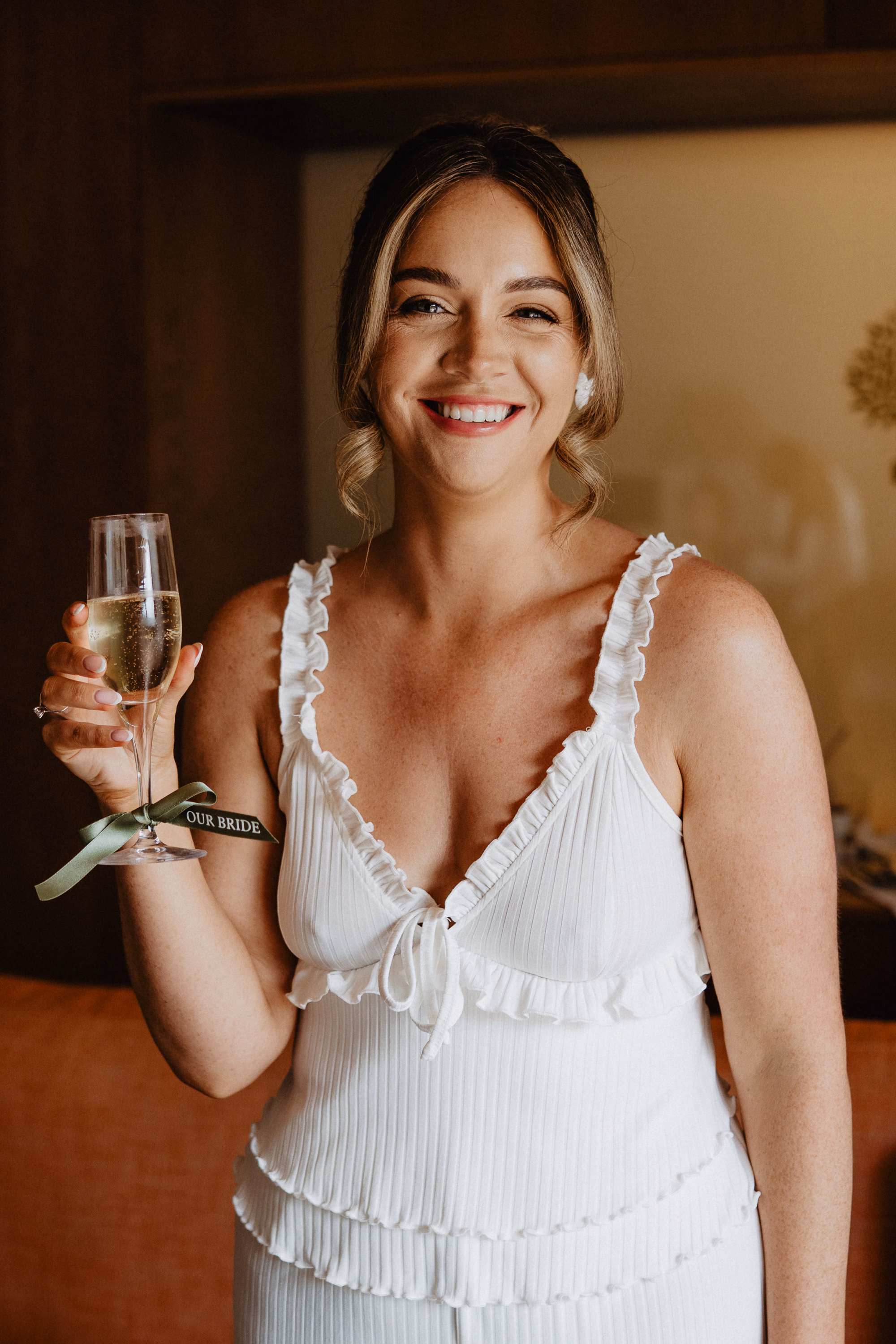 Happy bride holding a glass of champagne and smiling on her wedding day in Mallorca, planned by Dybiec Wedding